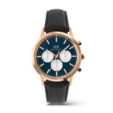 Daniel Wellington Iconic Chronograph watch in rose gold with an arctic blue dial, three white sub-dials, and a black leather strap.