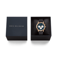 The Daniel Wellington Iconic Chronograph Sheffield watch in rose gold, featuring an Arctic blue panda dial and black leather strap, presented inside its black brand box.