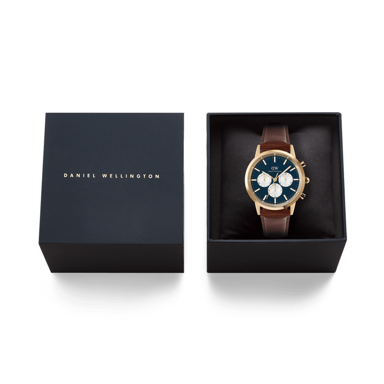 Daniel Wellington Iconic Chronograph St Mawes watch with a gold case, arctic blue panda dial, and brown leather strap, presented in its black gift box.